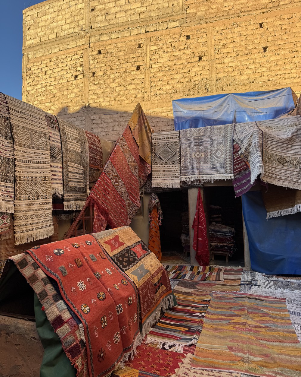 Handwoven Berber carpets in bright colours hanging in a village workshop in southern Morocco