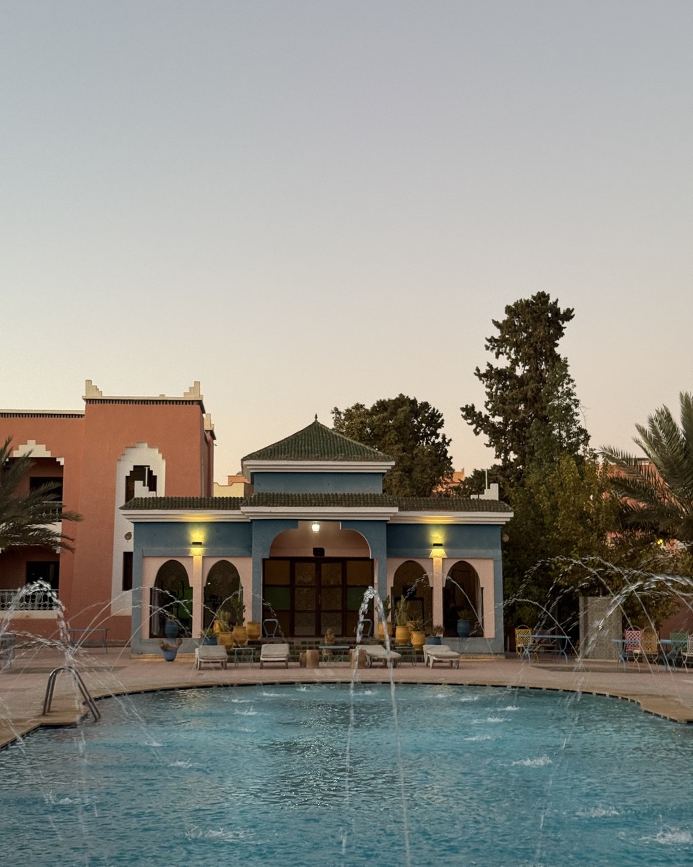 Hotel courtyard with a swimming pool, fountain and Moroccan arches on the Marrakech to Merzouga route