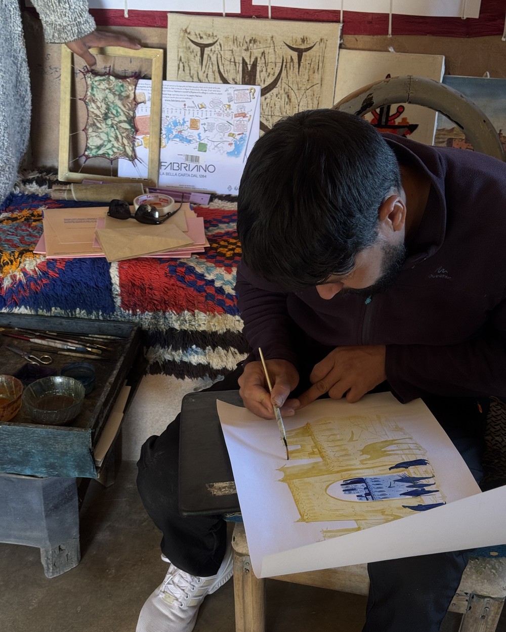 Artist painting with saffron and indigo pigment in a workshop on the road to the Sahara, Morocco