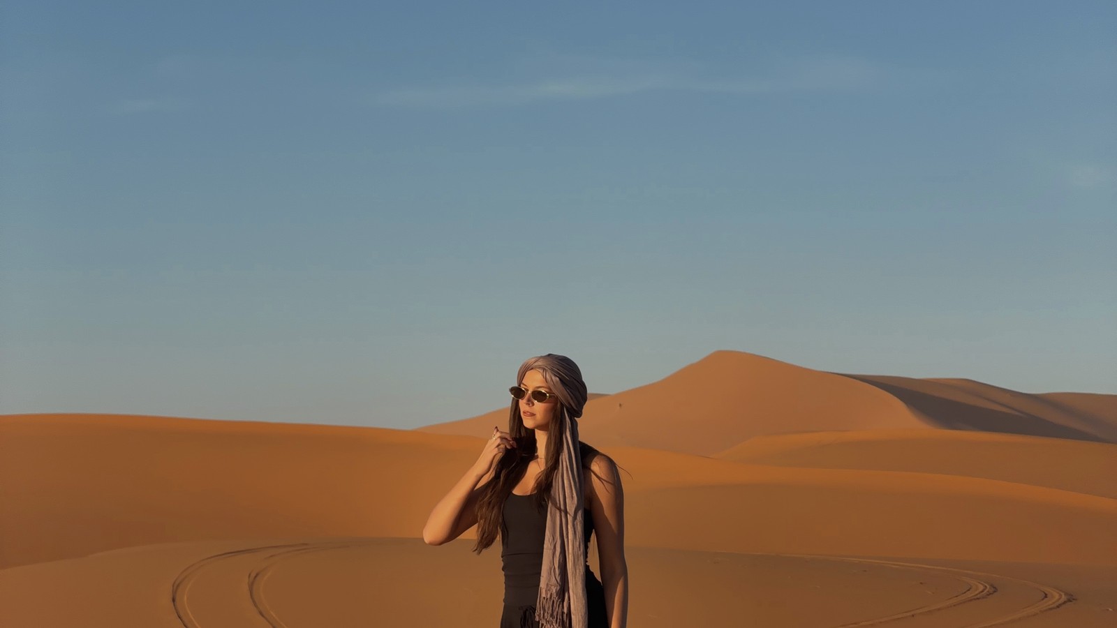 Ellen in a desert scarf standing on the sand dunes at Merzouga in the Sahara, Morocco