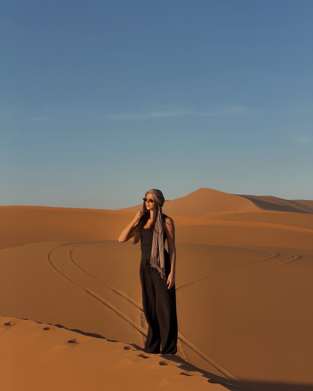Ellen in a desert scarf standing on the sand dunes at Merzouga in the Sahara, Morocco