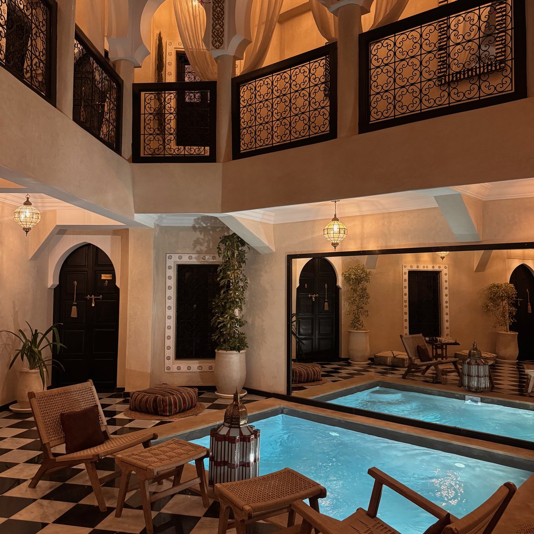 Tiled courtyard with a small pool lit up in the evening at Riad Zehra in Marrakech, Morocco