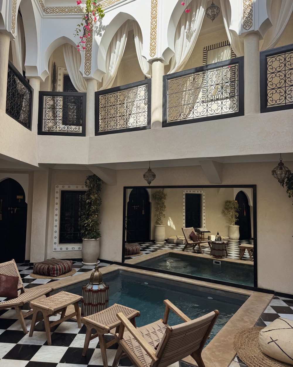 Black and white tiled courtyard with a plunge pool and seating at Riad Zehra in Marrakech, Morocco