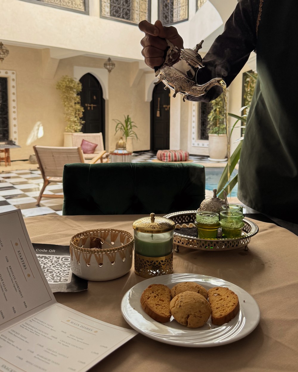 Moroccan mint tea being poured beside a plate of biscuits on arrival at a riad in Marrakech, Morocco