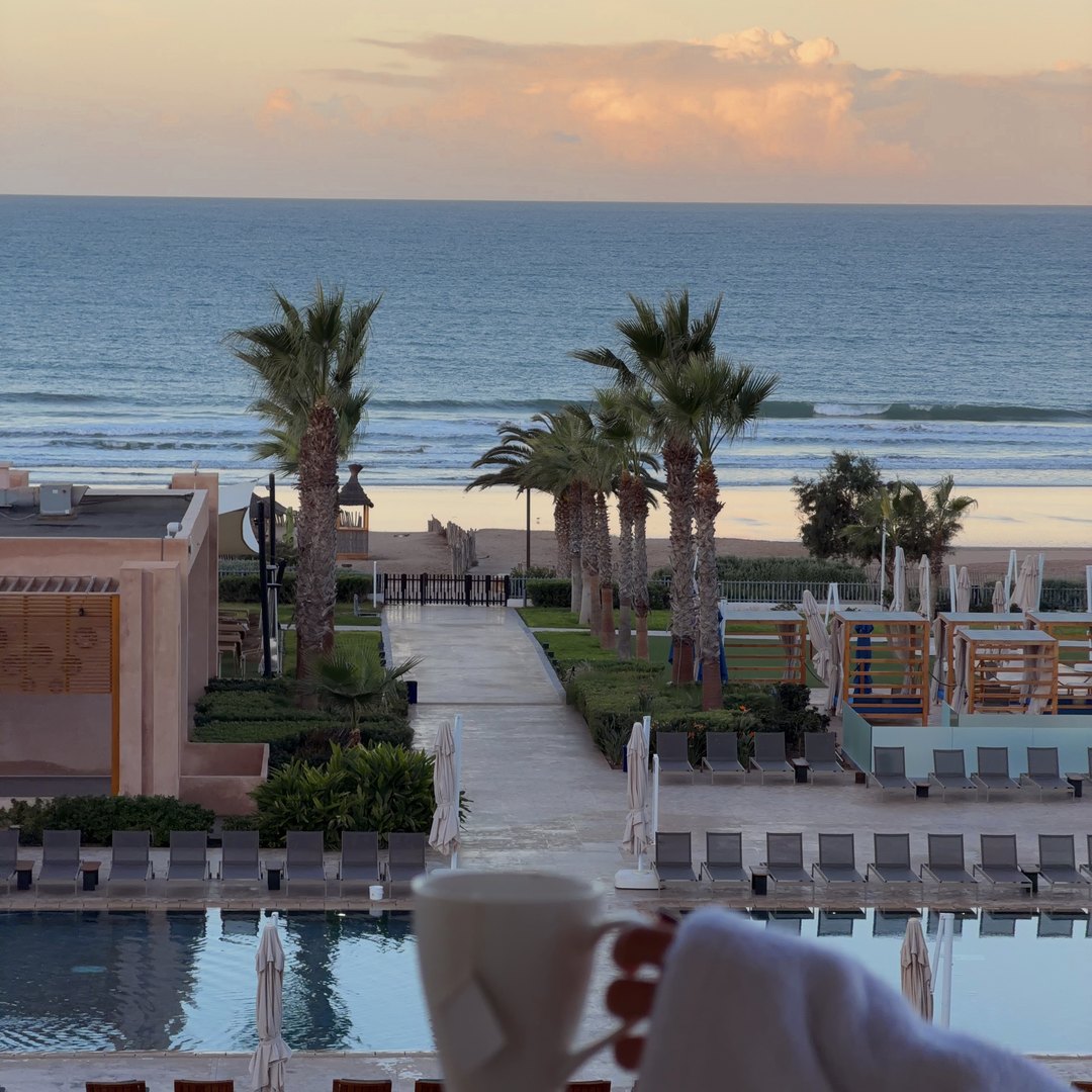 Pool and palm trees looking out over the beach at Hilton Taghazout Bay Beach Resort and Spa, Morocco