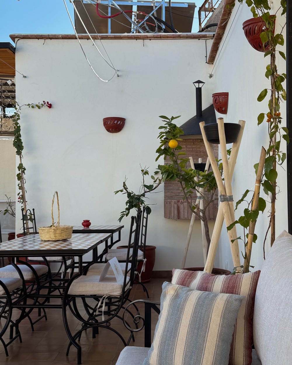 Rooftop terrace with a shaded dining area, plants and lanterns at a riad in Marrakech, Morocco
