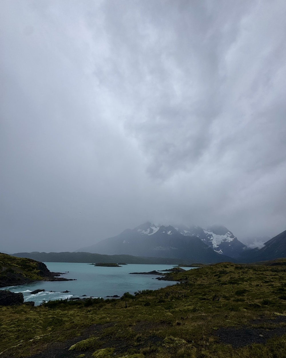 A turquoise lake under heavy grey cloud in Torres del Paine National Park