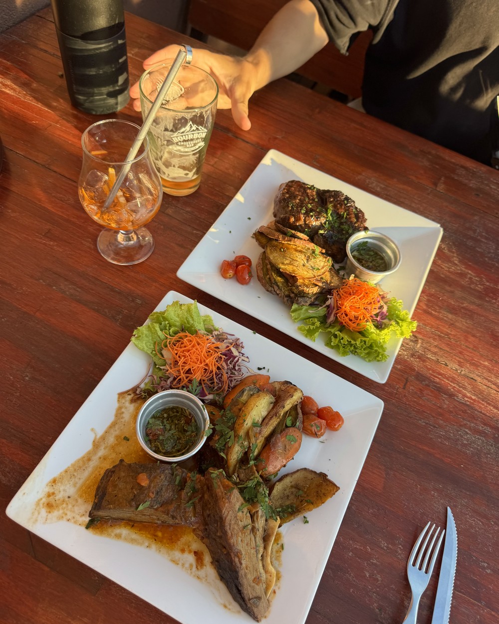 Ribeye with chimichurri and roast beef with potatoes at Bourbon Smokehouse in El Chaltén, with an Aperol and a beer