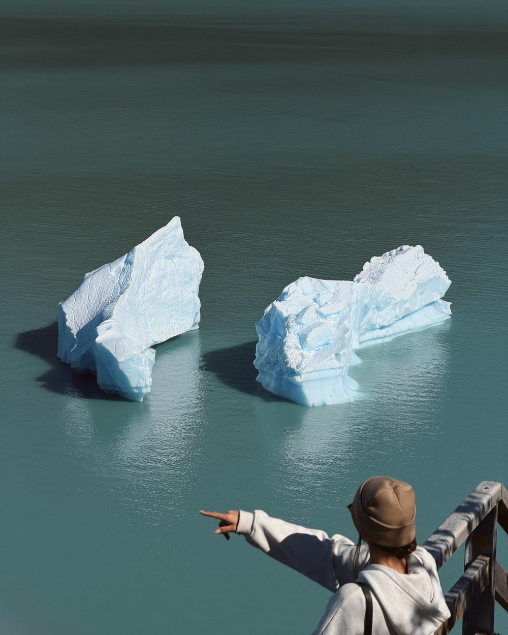 Ellen pointing at two icebergs from the walkways at Perito Moreno Glacier