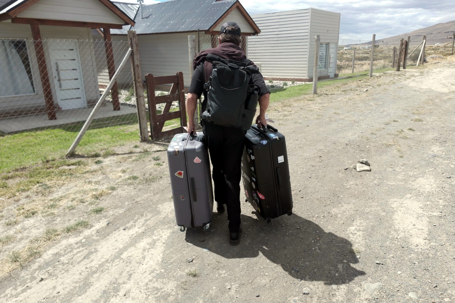 Daniel dragging two suitcases along a gravel street to our first Airbnb in El Calafate