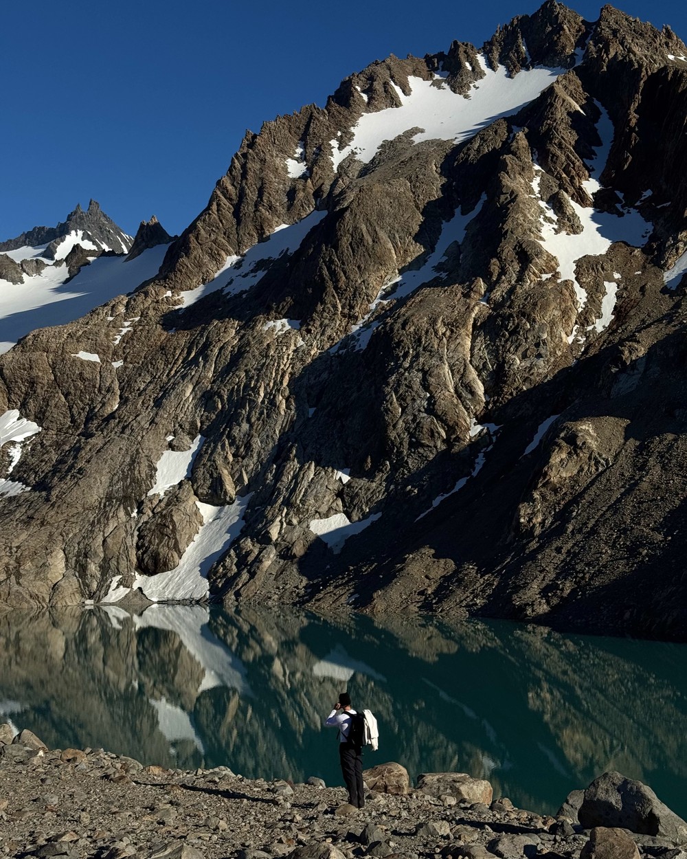 Daniel at the edge of Laguna de los Tres, the peaks reflected in the still water