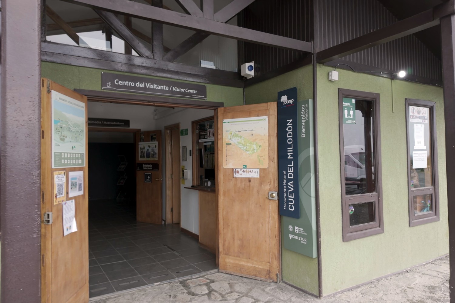 The open wooden doors of the Cueva del Milodón visitor centre, with the CONAF welcome sign beside them