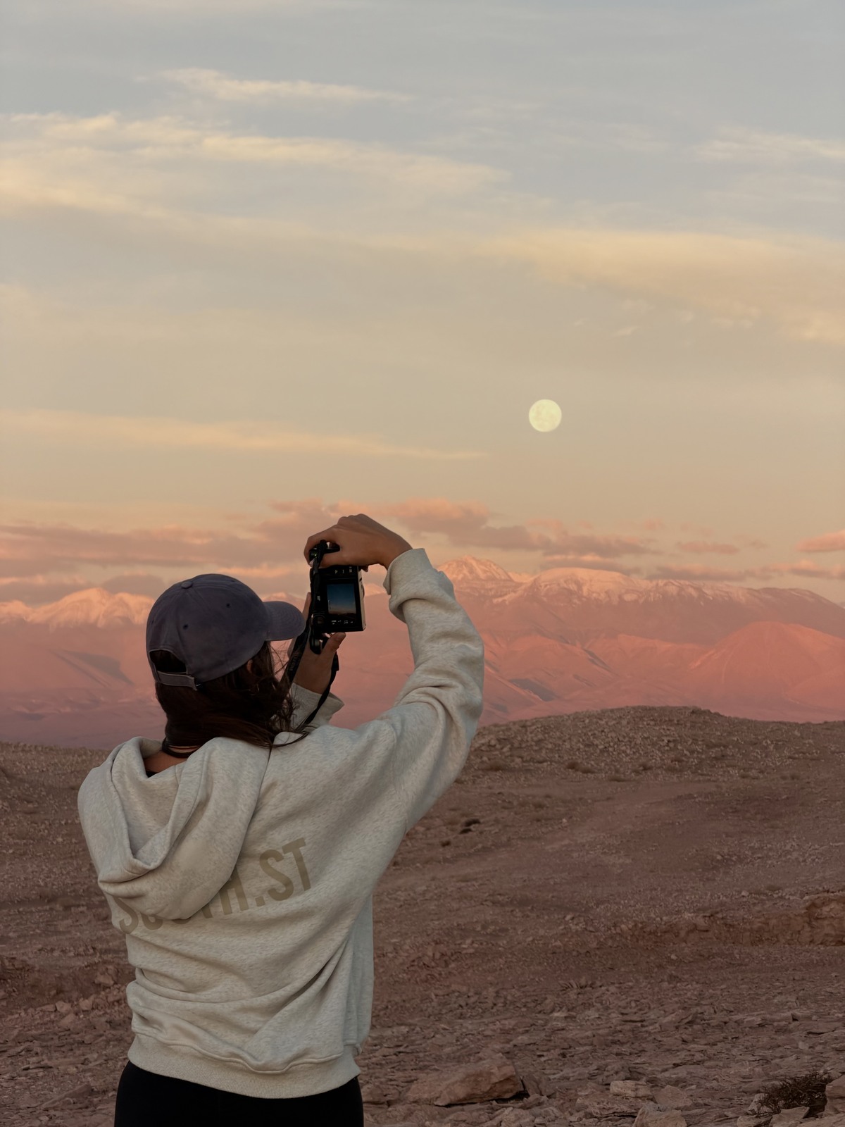 Ellen photographing the moon above pink mountains in the Atacama Desert