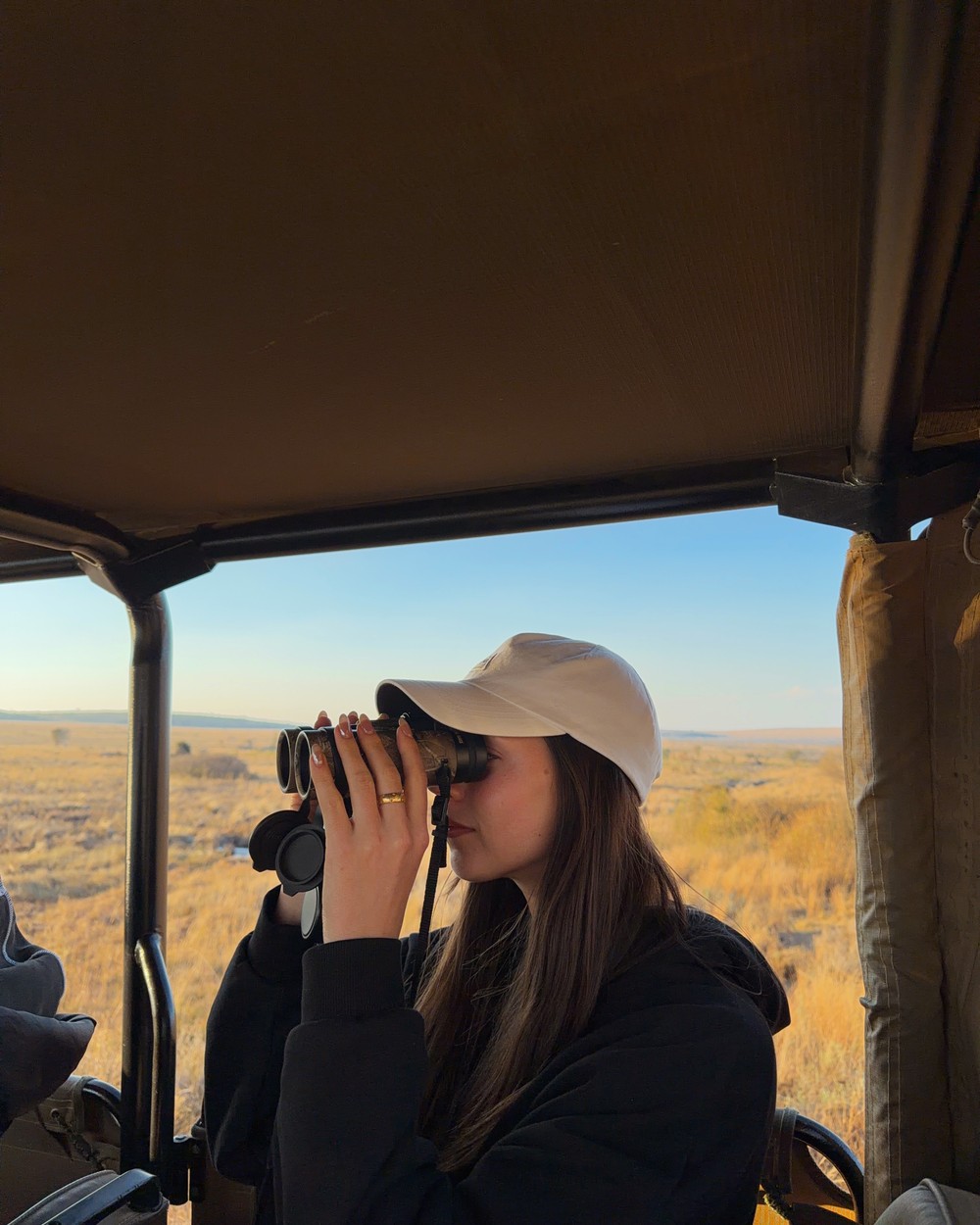 Woman looking through binoculars from a safari vehicle at Welgevonden Game Reserve