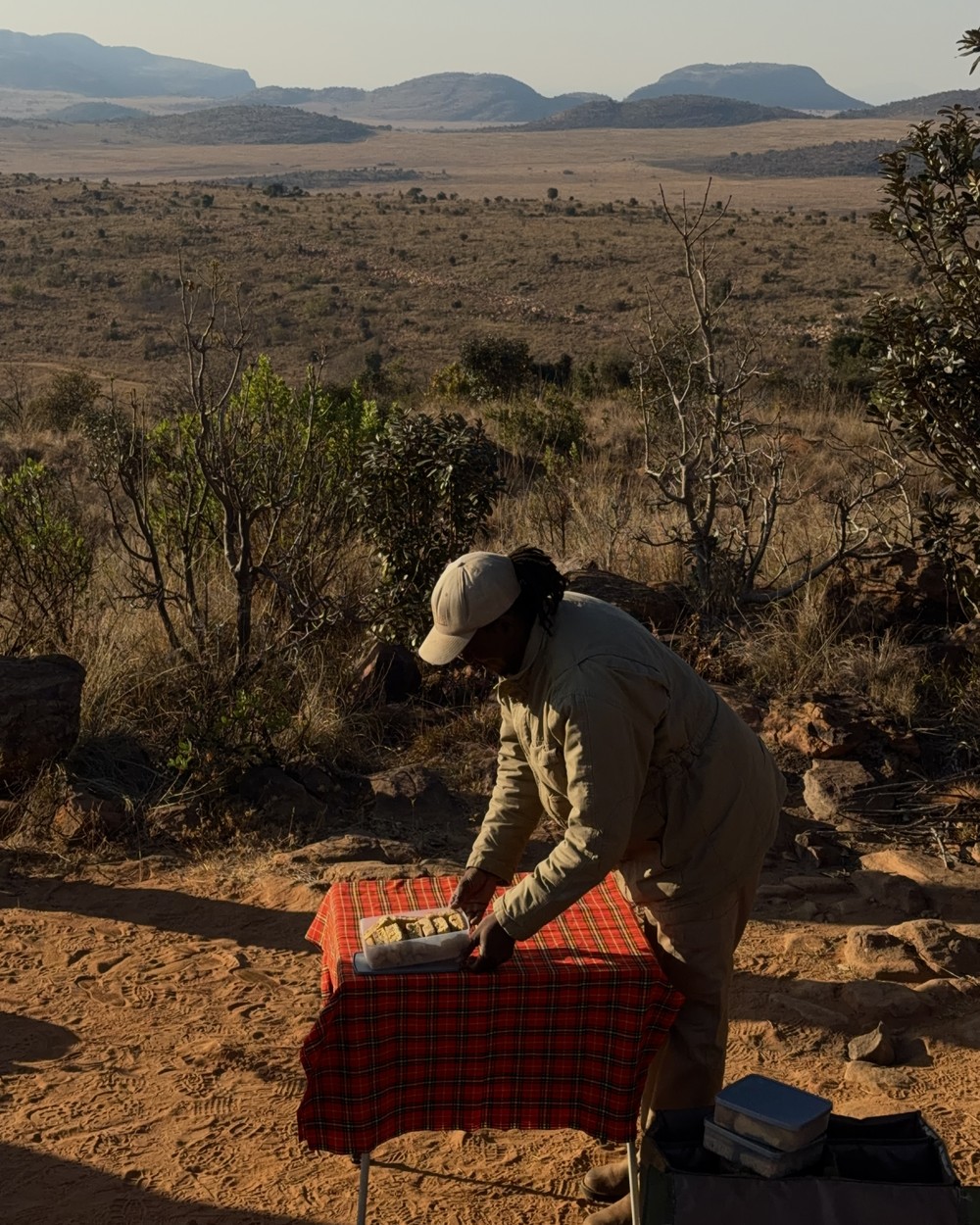 A guide setting up coffee and biscuits on a blanket during a morning game drive