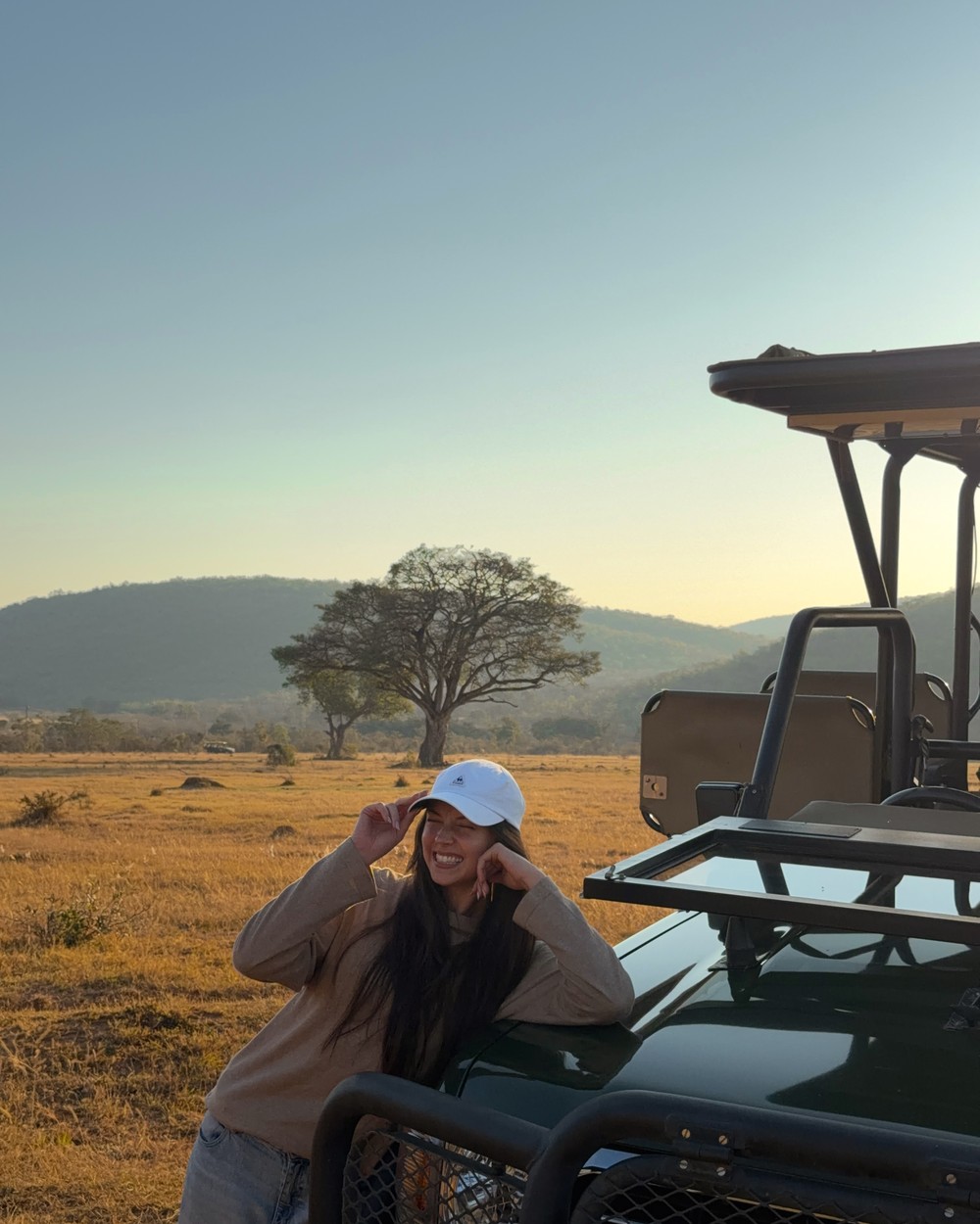 Woman sitting on the back of a safari vehicle in golden evening light