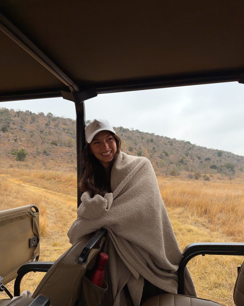 Woman wrapped in a blanket in a safari vehicle on a cold morning game drive