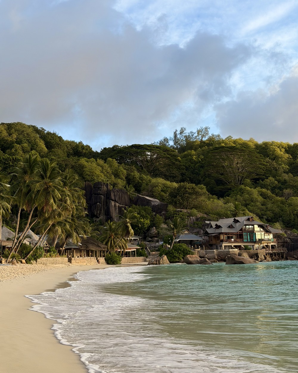 Palms and granite rocks beside white sand at Anse Takamaka on Mahe
