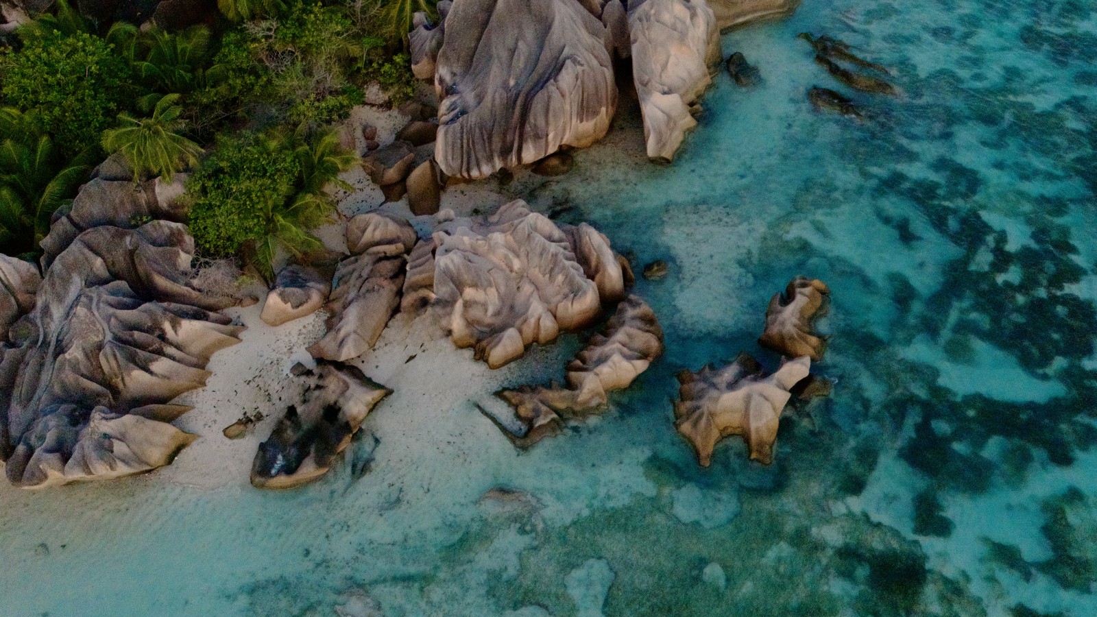 Aerial view of turquoise shallows, white sand and granite boulders at Anse Source d'Argent on La Digue