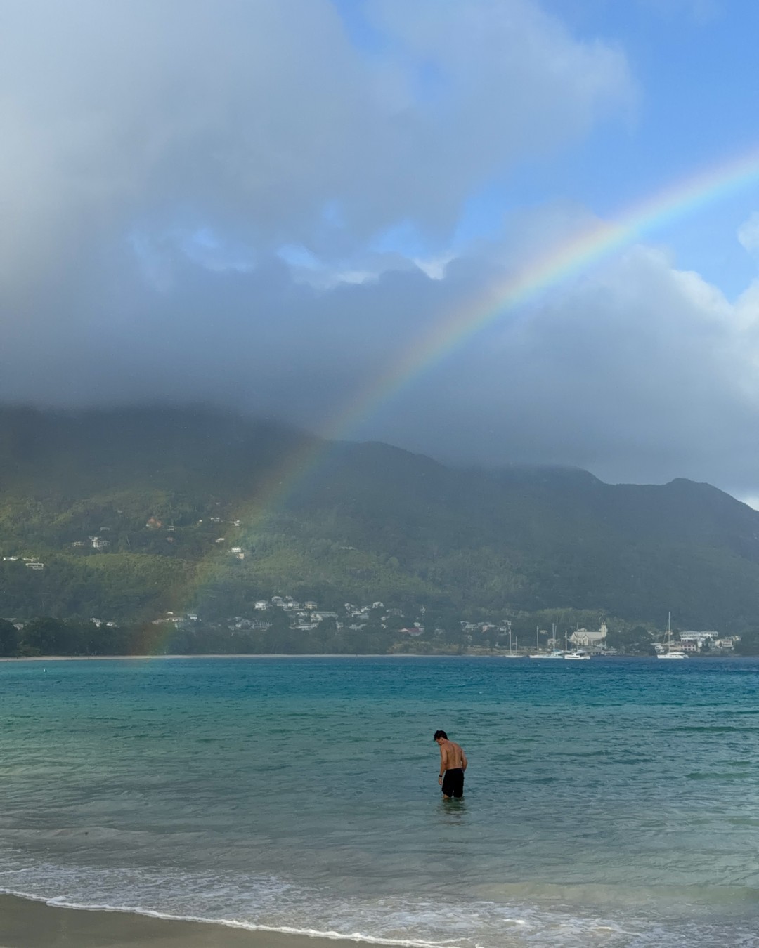 A rainbow above Beau Vallon beach and the green mountains of Mahe in Seychelles