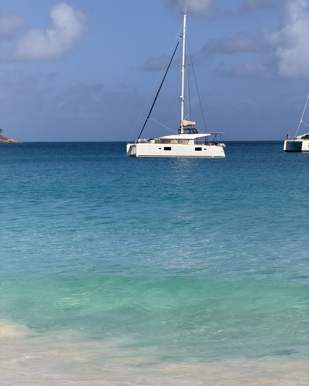 A white catamaran anchored in deep blue water off Anse Lazio on Praslin, Seychelles