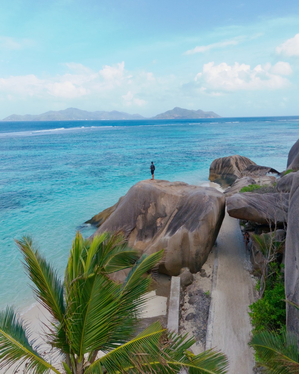 Daniel standing on a giant granite boulder above Anse Source d'Argent on La Digue