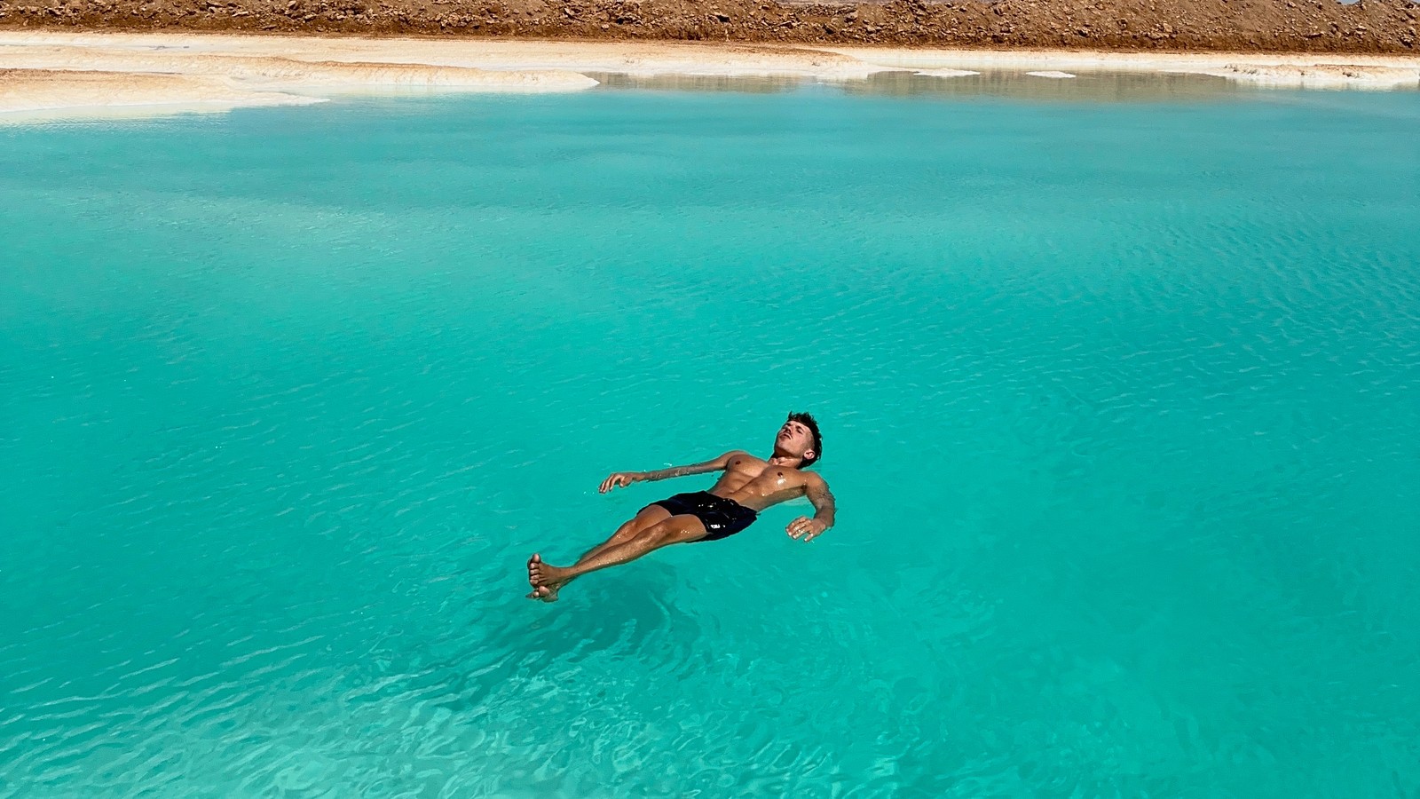 Daniel floating in a turquoise salt lake in Siwa Oasis, Egypt