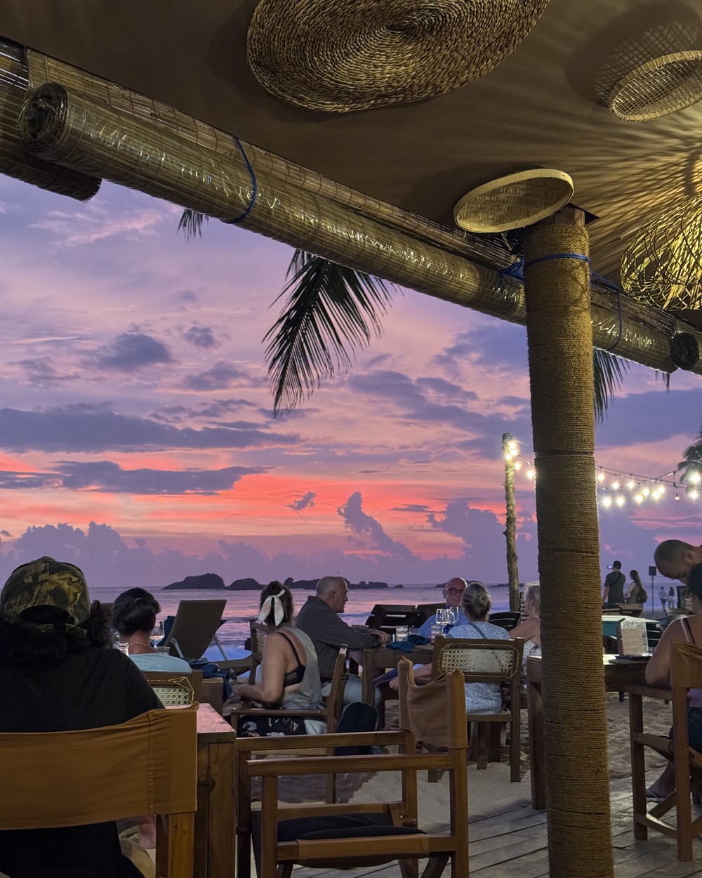 Empty chairs and tables on the sand at a beach cafe under a grey sky in southern Sri Lanka