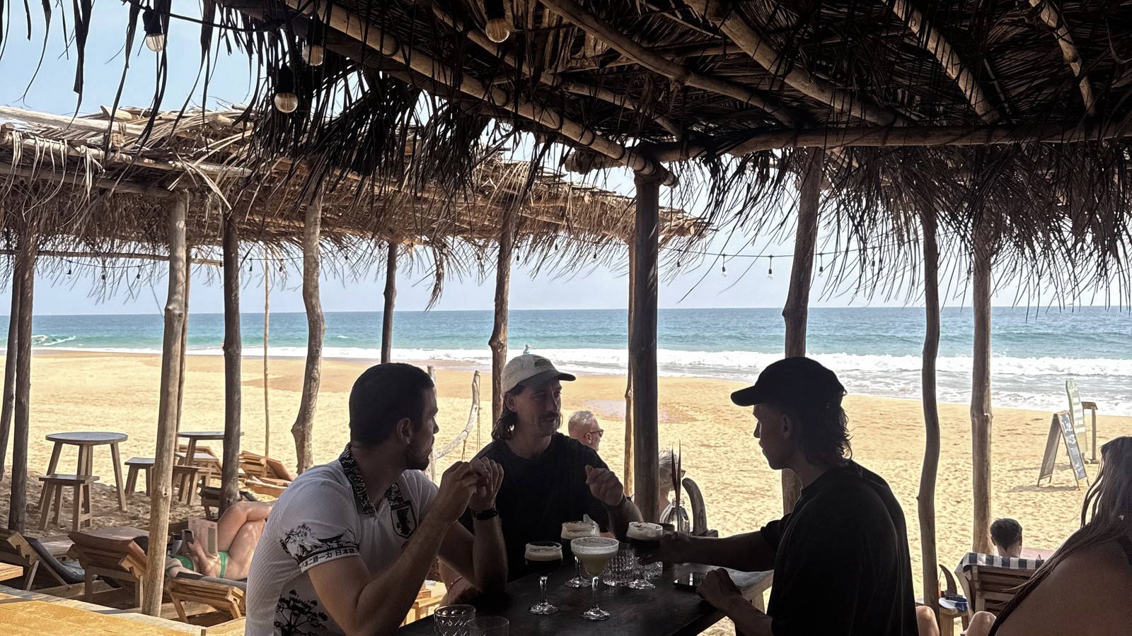 Beach cafe under a thatched roof looking out over the sand and sea at Hikkaduwa, Sri Lanka