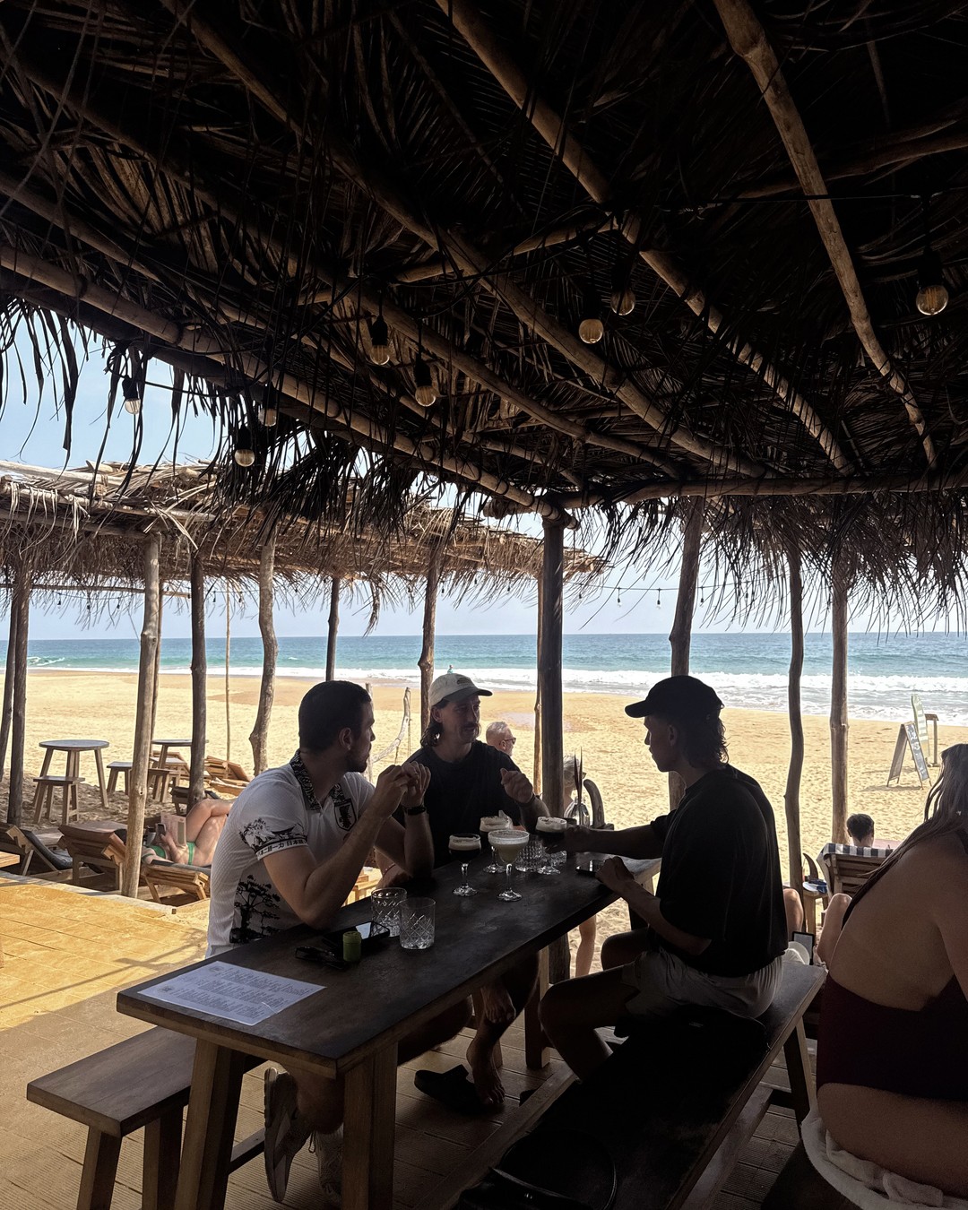 Beach cafe under a thatched roof looking out over the sand and sea at Hikkaduwa, Sri Lanka