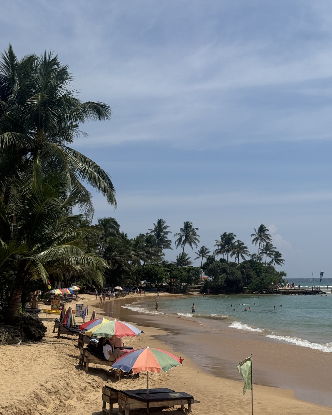 Palm trees leaning over shallow turquoise water at Hikkaduwa beach, Sri Lanka