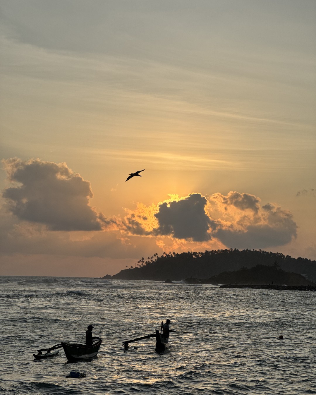 Fishermen in outrigger canoes on calm water at sunset on the south coast of Sri Lanka