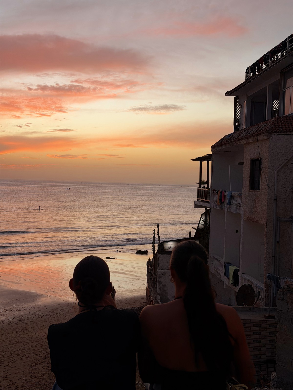 Two people looking over Taghazout beach at sunset
