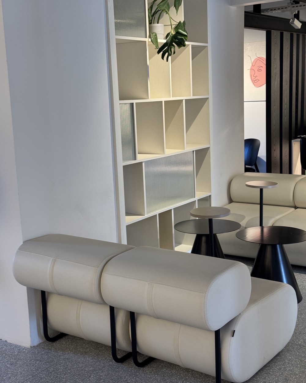 Minimal white cafe interior with bench seating and small round tables in Antalya