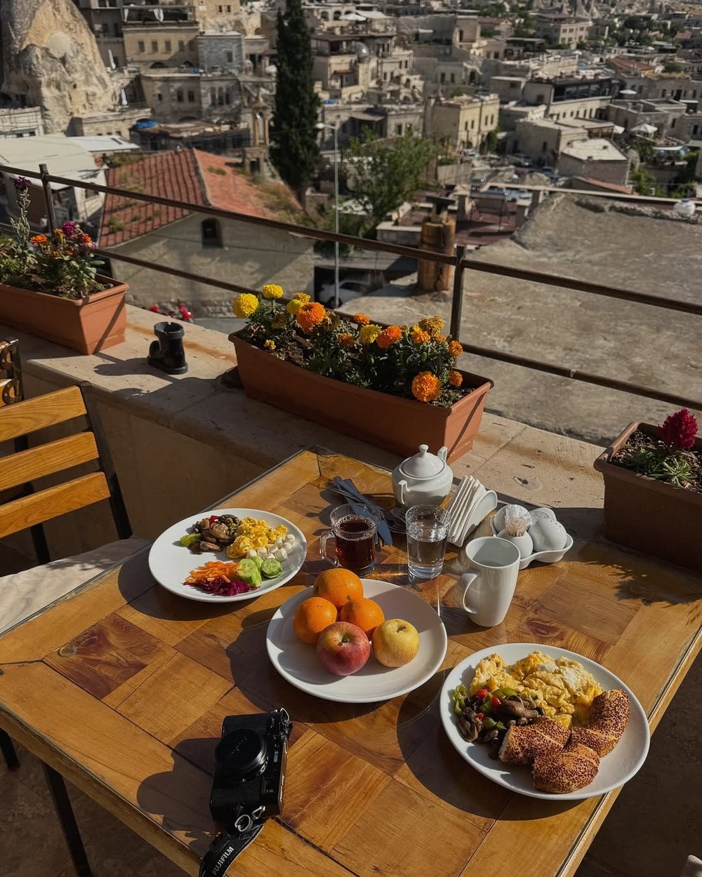 Breakfast plates, fruit and Turkish tea on a rooftop table overlooking Cappadocia
