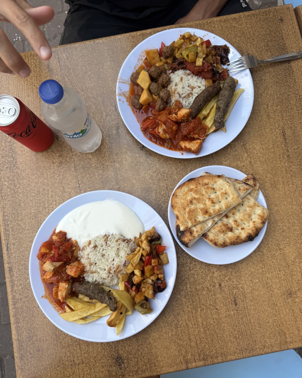 Two plates of Turkish stew with rice, chips and flatbread on a wooden table in Antalya