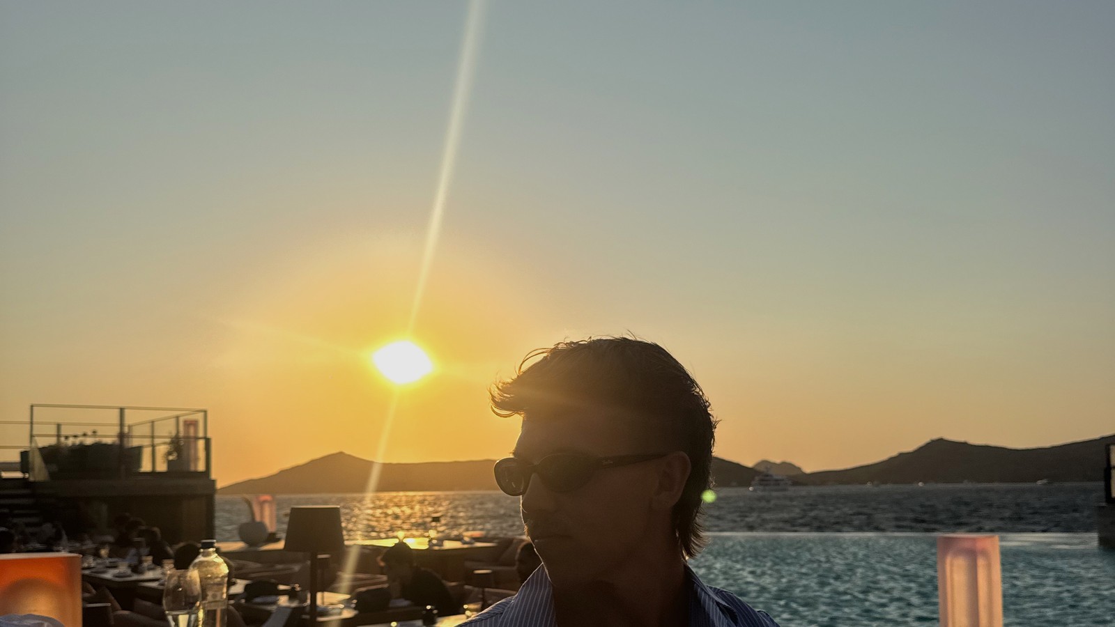 Sunset over the bay behind the Zuma restaurant sign in Bodrum, Türkiye