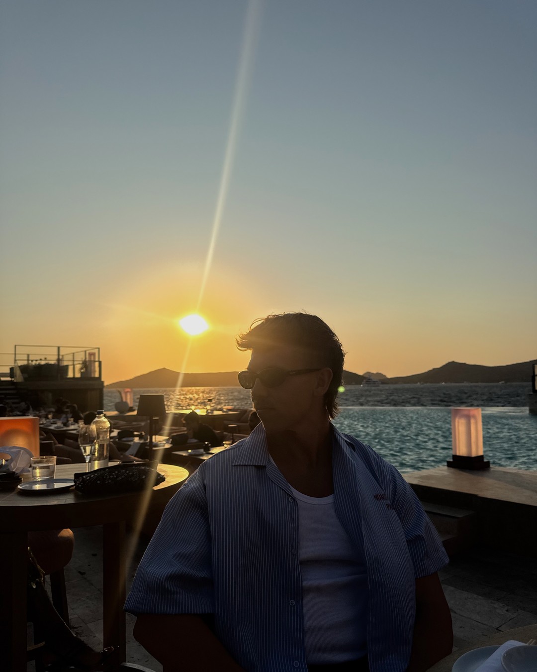Sunset over the bay behind the Zuma restaurant sign in Bodrum, Türkiye