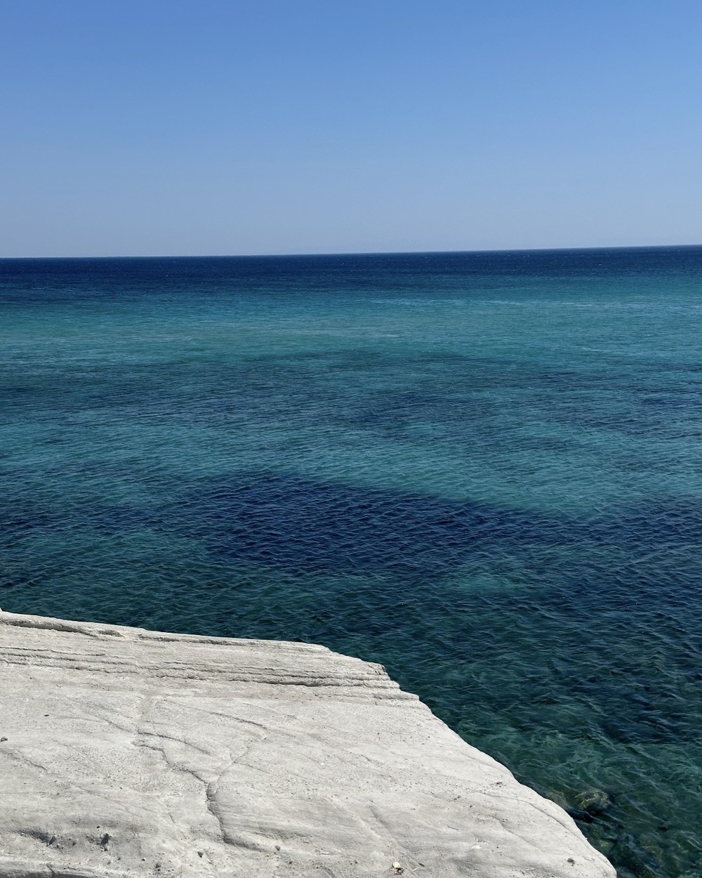Blue metal steps leading down white rock ledges into clear turquoise water at Delikli Koy