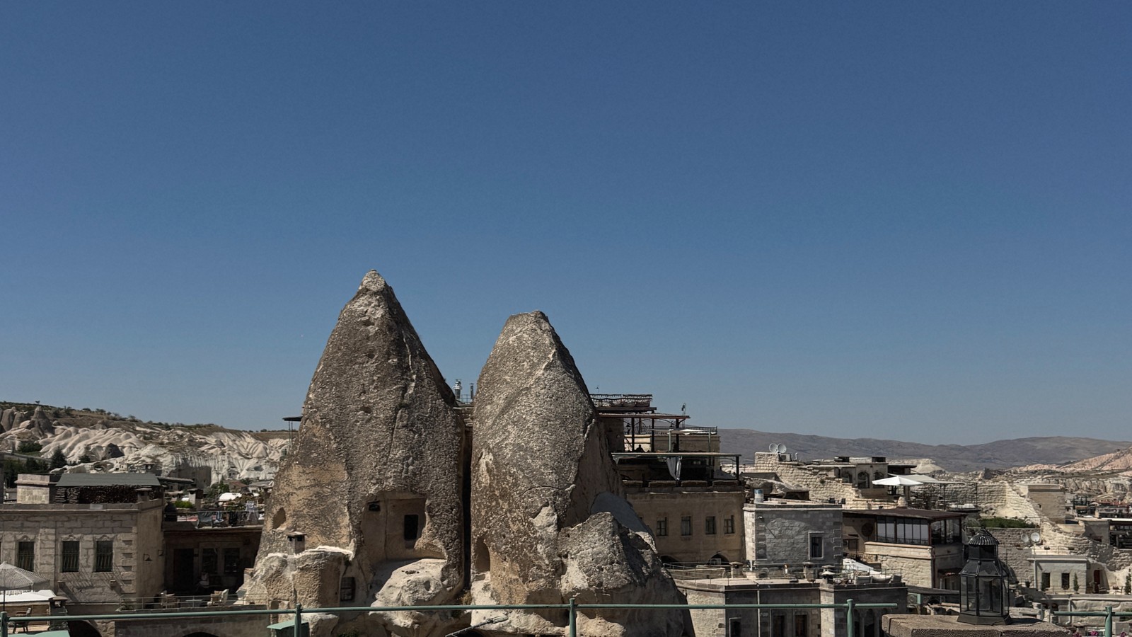 Fairy chimneys and cave houses above a rooftop terrace in Cappadocia, Türkiye