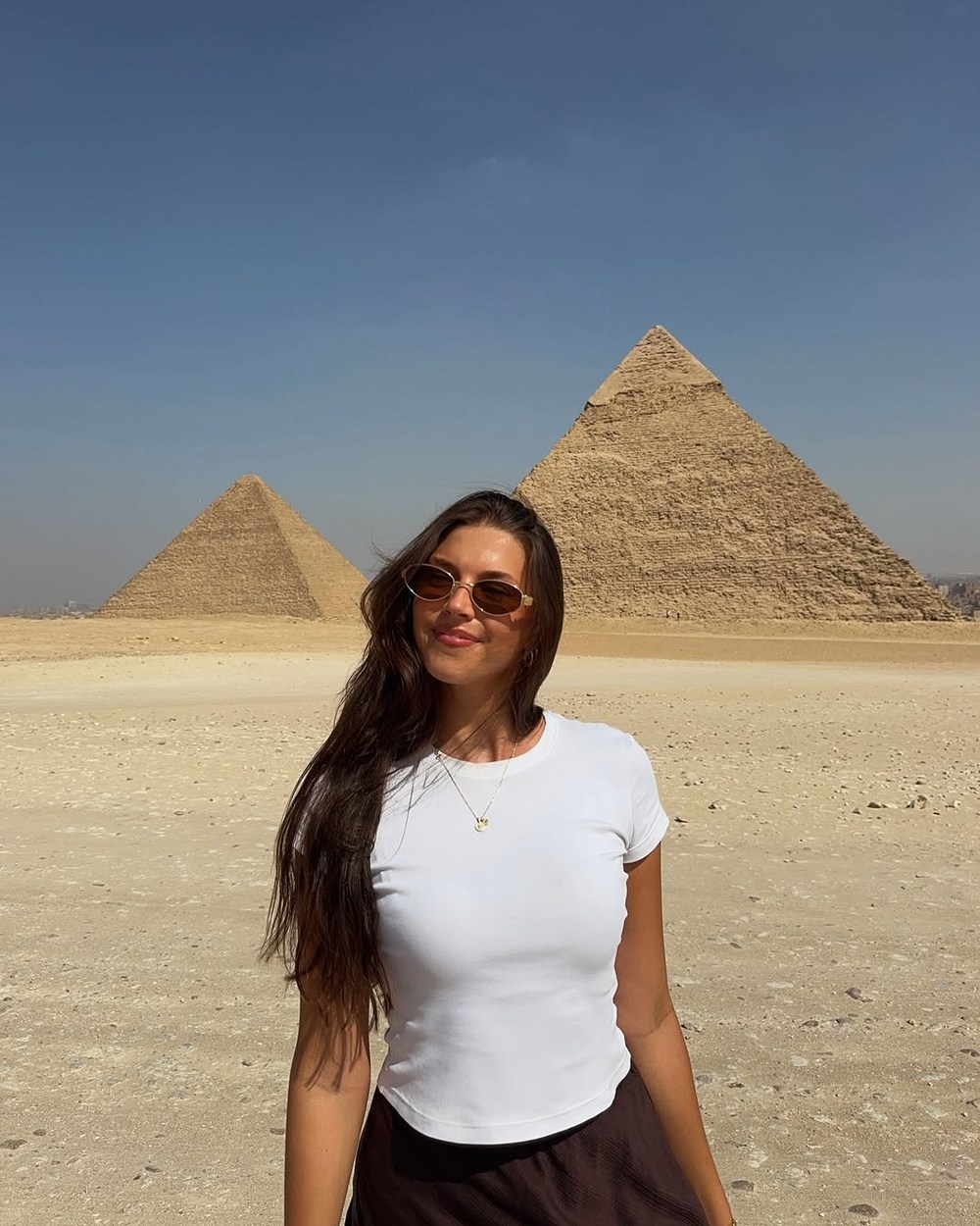 Ellen wearing a white T-shirt and long skirt in front of the Pyramids of Giza