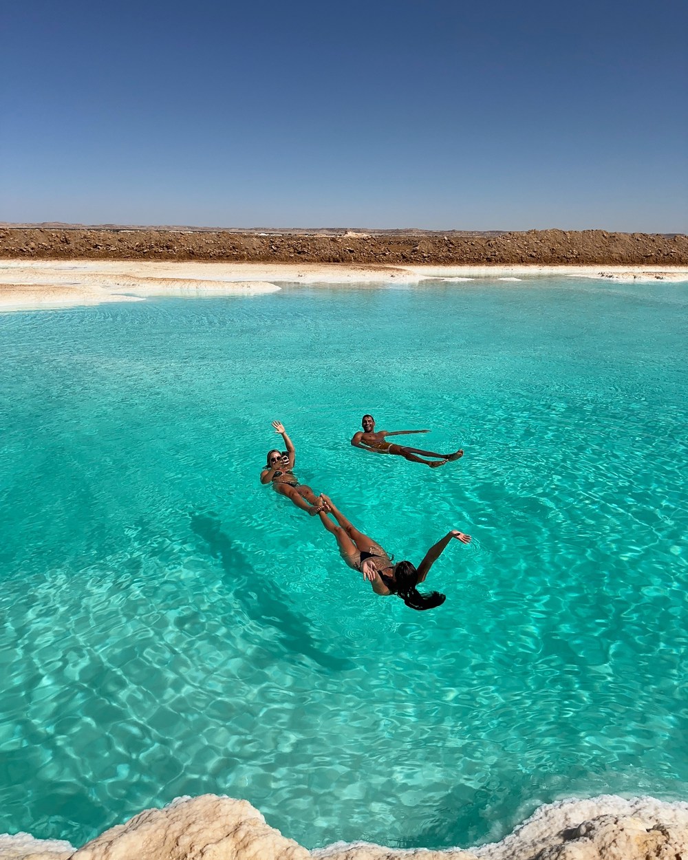Ellen and friends floating in the turquoise salt lakes of Siwa Oasis