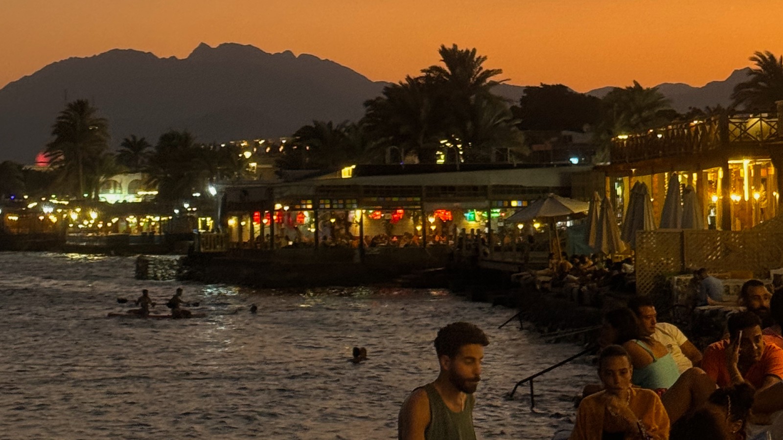 Dahab's waterfront and mountains glowing at sunset beside the Red Sea