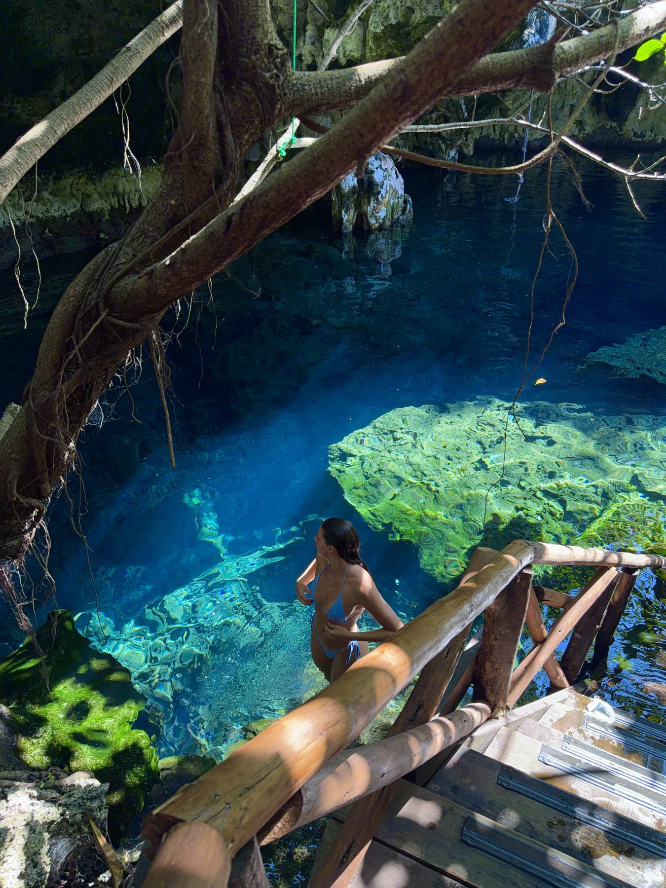 Ellen descending the wooden steps into the blue natural pool at Maalum Cave