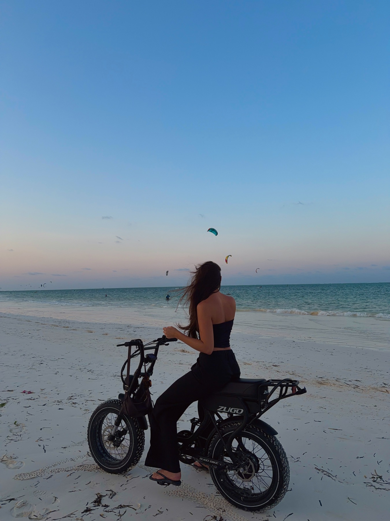 Ellen on a bike beside Paje beach as the evening light fades
