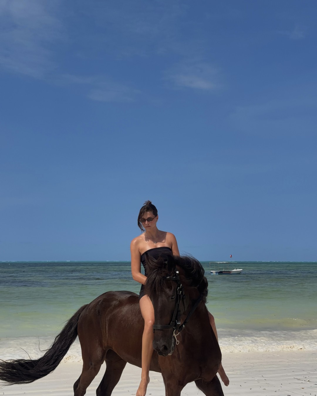 Ellen riding a horse along the shallow turquoise water at Jambiani beach in Zanzibar