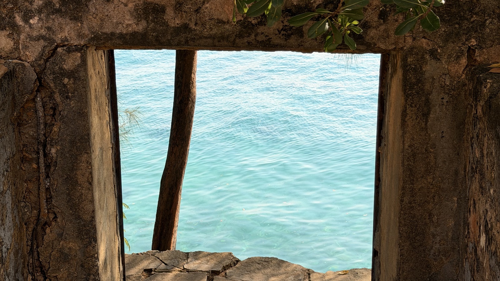 Turquoise water framed by a weathered stone opening on Prison Island, Zanzibar