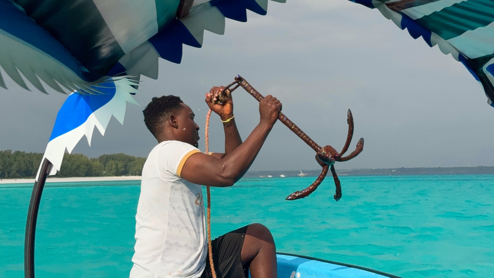 Our boat guide lifting the anchor above turquoise water near Mnemba, Zanzibar