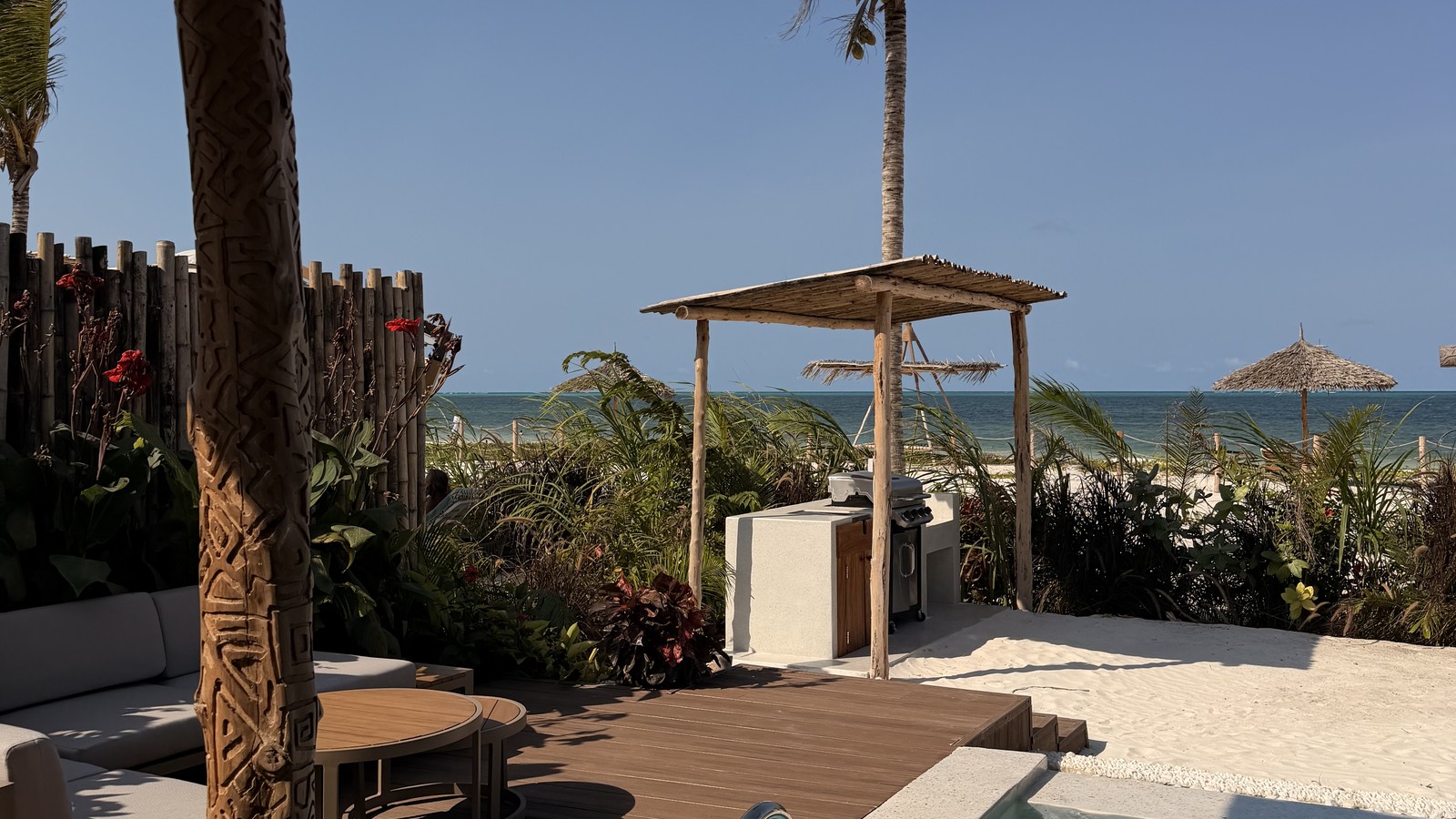 Thatched beach cabana, white sand and the ocean at a beachfront lodge in Paje, Zanzibar
