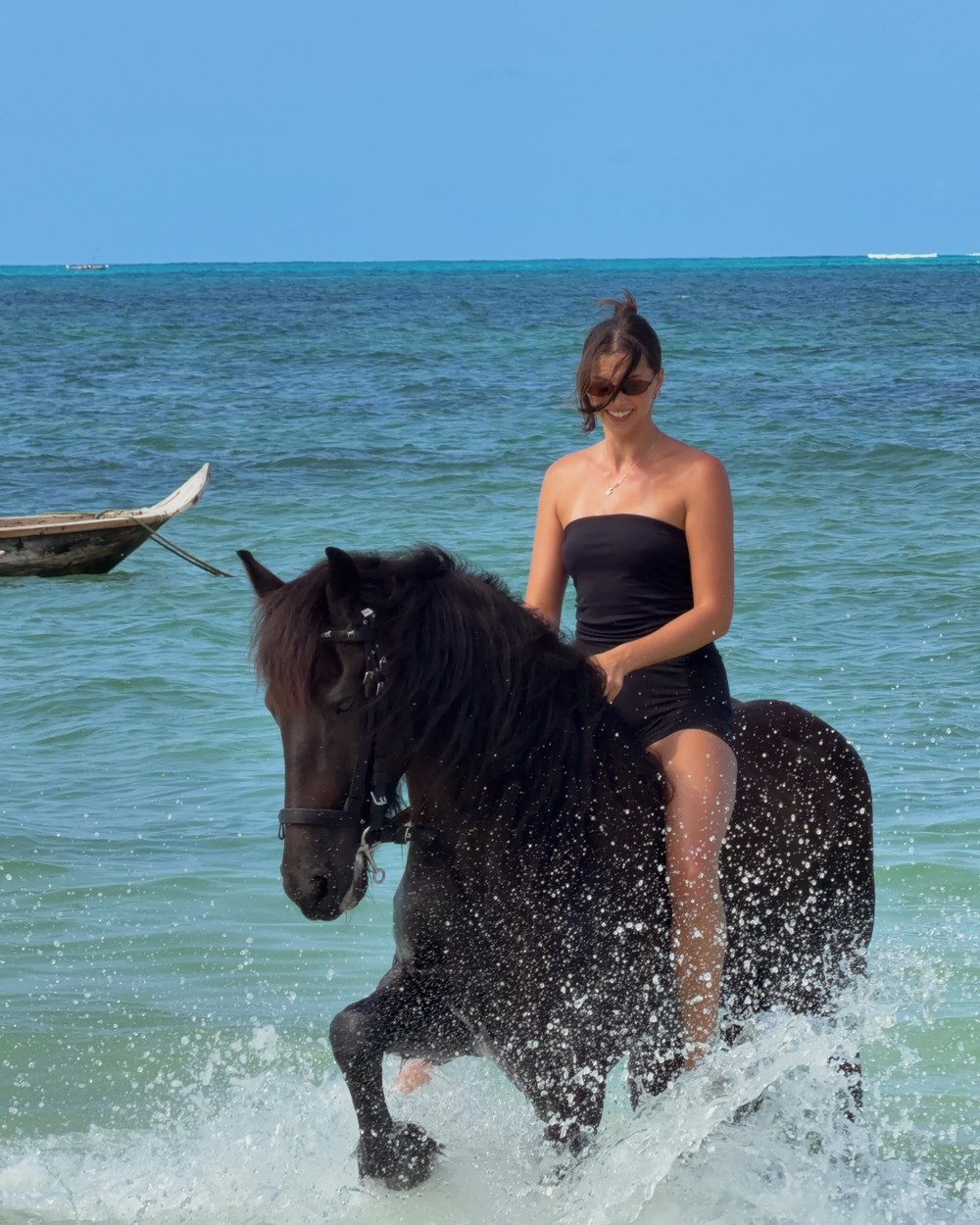 Riding a horse into the shallow water at Jambiani beach in Zanzibar